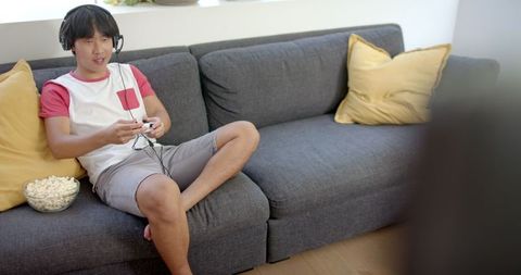 Man Relaxing on Couch Listening to Music with Smartphone