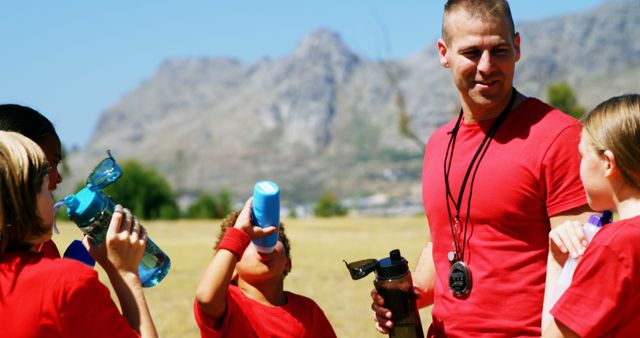 Trainer and kids drinking water in the boot camp on a sunny day