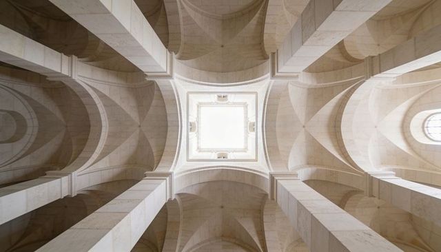 Symmetrical limestone groin vaults and massive piers framing central skylight in cathedral