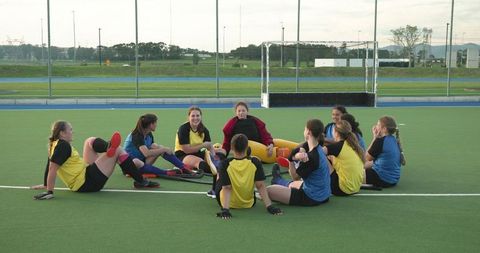 Female Field Hockey Team in Circle Stretching and Socializing