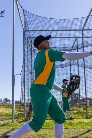 Catcher reaching and catching ball in batting cage during team practice