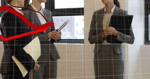 Businesswomen holding folders and tablet presenting corporate analytics red trend line
