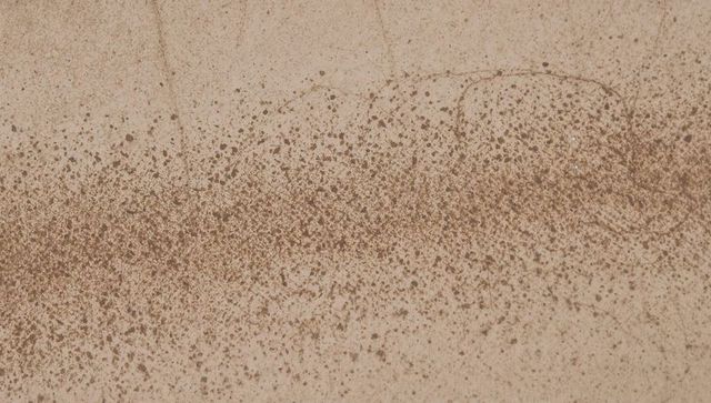 Brown speckle band spreading across beige grunge surface with droplet stain texture