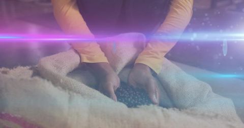 Woman cupping roasted coffee beans in burlap sack closeup with warm lens flare