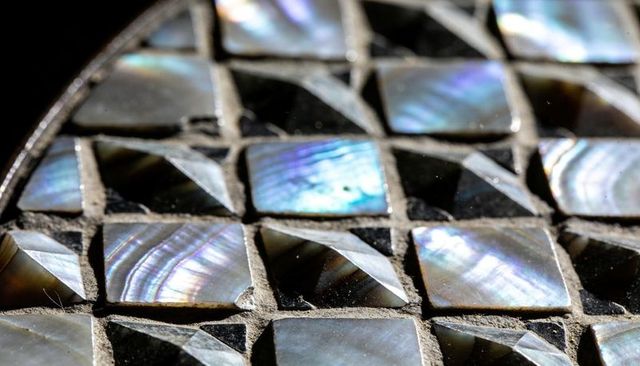 Iridescent mother-of-pearl mosaic tiles showing beveled nacre squares on tabletop
