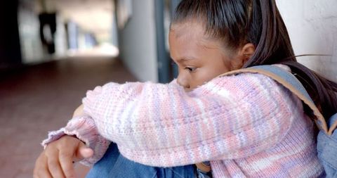 Lonely Schoolgirl Sitting in Hallway Lost in Thought