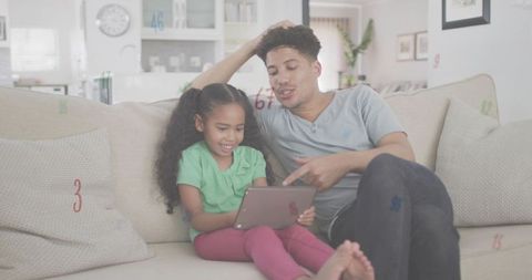 Father and daughter sharing tablet on sofa, interactive learning and cozy family moment