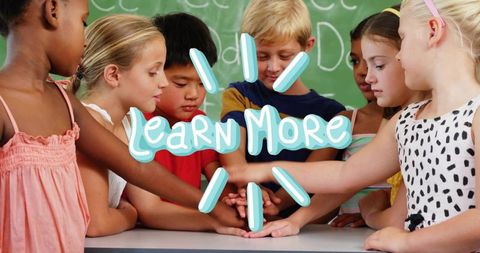 Elementary Students Stacking Hands in Classroom Showing Teamwork and Collaborative Learning