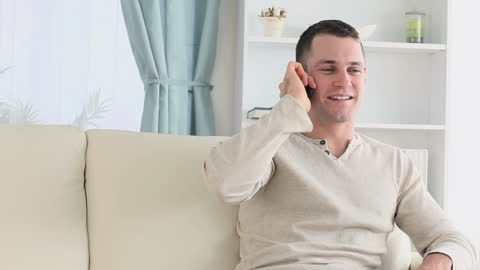 Man Cheerfully Conversing on Smartphone While Relaxing