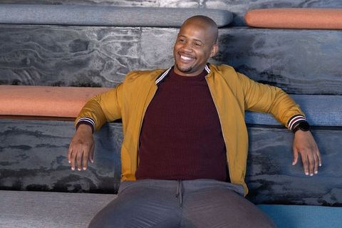African american man relaxing on tiered lounge bench wearing mustard jacket and watch