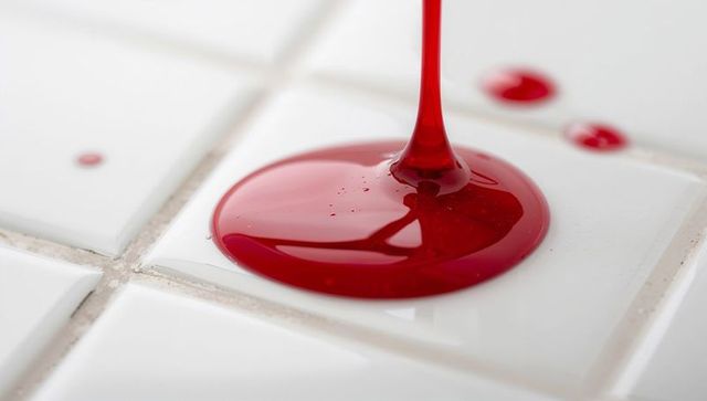 Glossy red liquid on white ceramic tiles with grout