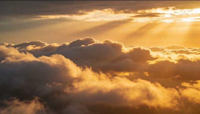 Golden Sunbeams over Billowy Cumulus Clouds from High-Altitude Panoramic View