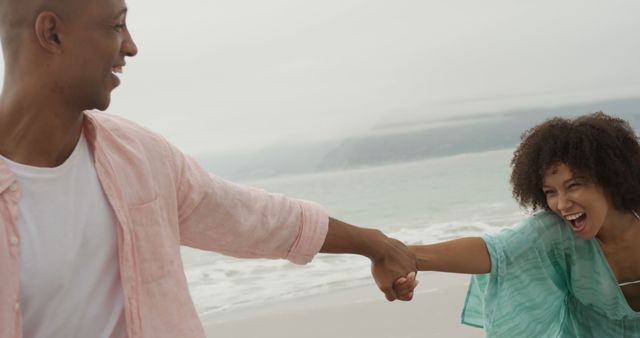 Happy african american couple holding hands on beach. Lifestyle, relationship, togetherness, summer, leisure and vacation, unaltered.
