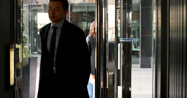 Businessman in suit exiting modern office building - Download Free Stock Images Pikwizard.com