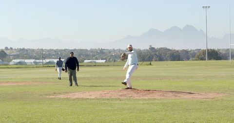 Right-Handed Pitcher Delivering Fastball on Baseball Mound with Umpire and Teammates