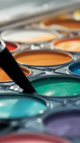 Vertical watercolor close-up dipping paintbrush into vibrant palette, loading pigment for painting