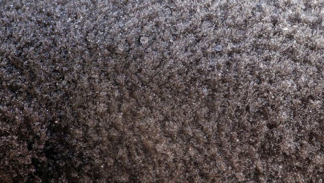 Frost forming on fibrous surface with sparkling ice crystals and frozen droplets