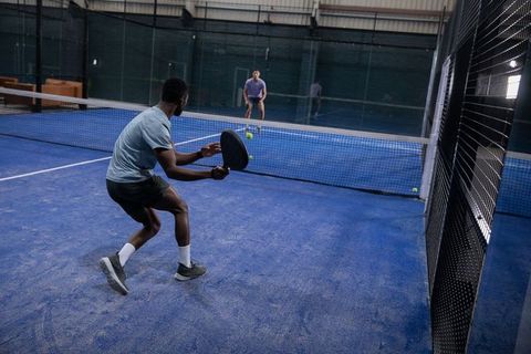 Competitive indoor padel match with diverse male players showcasing fast rally
