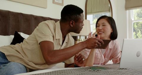 Interracial Couple Planning Wedding on Laptop in Cozy Environment