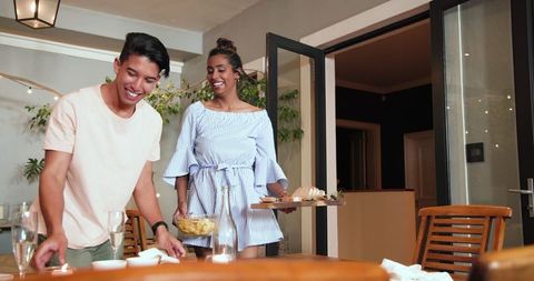 Diverse Young Couple Clearing Dinner Table After Party