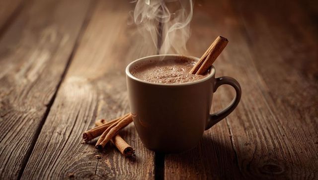 Steaming hot beverage in rustic mug with cinnamon