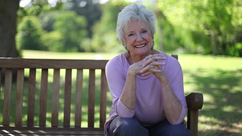Senior Woman Relaxing on Park Bench with Warm Smile