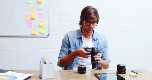 Young Photographer Preparing Camera Equipment at Modern Office Desk - Download Free Stock Images Pikwizard.com