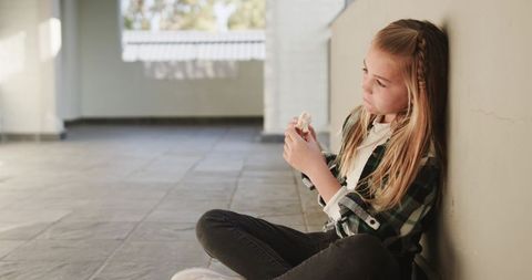 Thoughtful child sitting alone indoor enjoying sandwich
