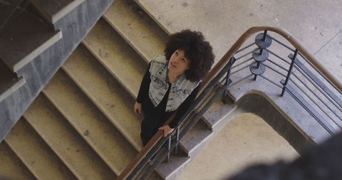 Woman ascending spiral staircase in urban setting