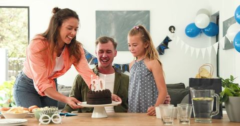 Family Celebrating Father's Birthday with Cake and Balloons