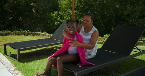 Grandmother Wrapping Pink Towel Around Granddaughter Outdoors
