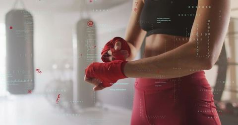 Athletic woman wrapping red hand wraps in boxing gym, boxing training and strength
