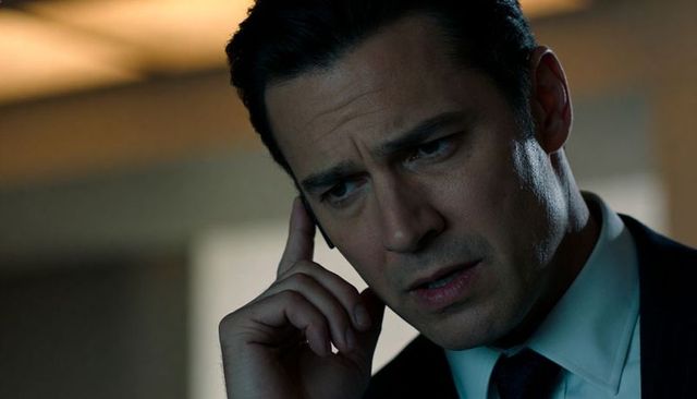Corporate executive listening intently during urgent call, focused professional headshot