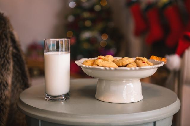 Christmas cookies and milk on table with blurred decorated Christmas tree in background. Perfect for holiday-themed articles, festive greeting cards, or baking promotions. Creates warm, inviting atmosphere ideal for celebrating, sharing seasonal recipes, or illustrating family traditions.