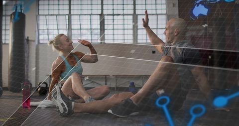 Fitness partners high-fiving on mat in industrial gym with futuristic hud overlay and training gear