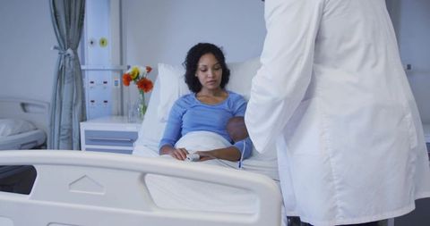 Doctor examining female patient with pulse oximeter on finger at bedside in hospital room