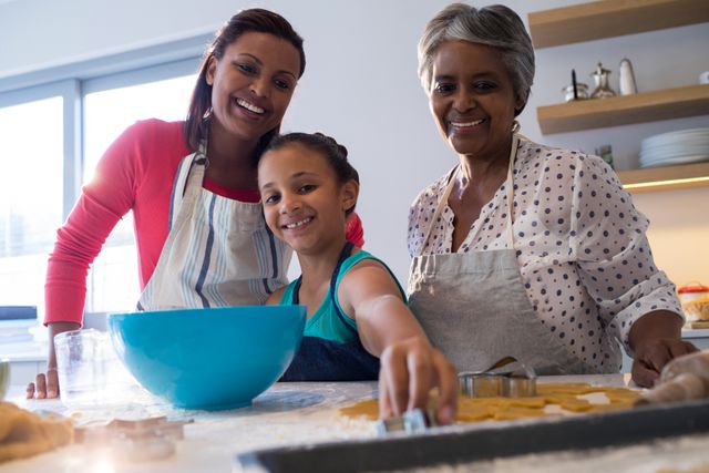 Three generations of women enjoying baking cookies together in a bright kitchen. This image can be used for promoting family bonding activities, cooking classes, or home baking products. It highlights the joy and togetherness of family life.