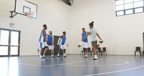 Diverse Team Warming Up for Basketball Game in Indoor Gym