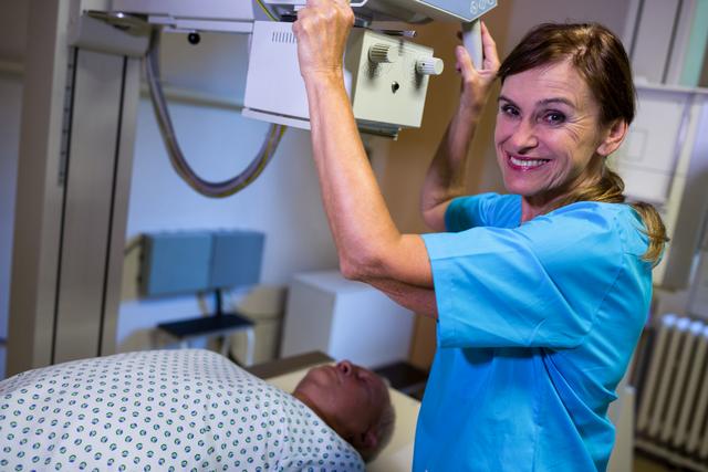 Radiologist in blue scrubs preparing patient for x-ray examination. Ideal for use in healthcare, medical, and hospital-related content, showcasing medical procedures, patient care, and professional healthcare services.