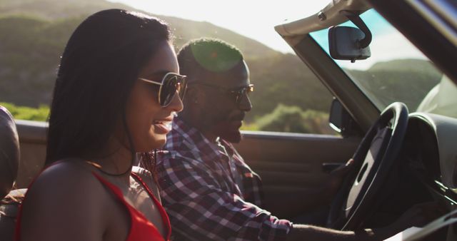 African american couple using map while sitting in convertible car. road trip travel and adventure concept