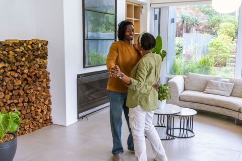 African american couple dancing in modern living room near stacked firewood and garden view