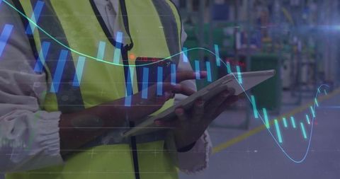 Female technician tapping tablet on factory floor with candlestick chart analytics overlay