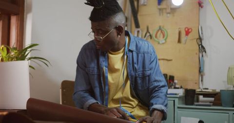 Focused craftsman sketching designs in leather workshop