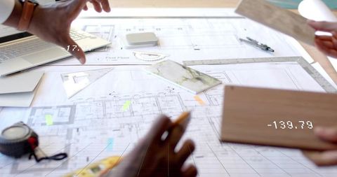 Architects Collaborating on Floor Plan with Blueprints and Samples