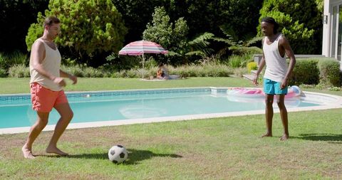 Friends enjoying soccer by pool during summer