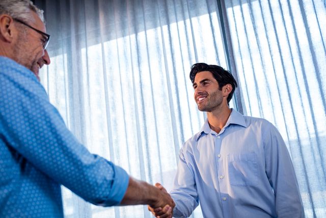 Two businessmen shaking hands in an office setting, symbolizing agreement, partnership, and successful collaboration. Ideal for use in business-related content, articles on professional relationships, corporate websites, and promotional materials highlighting teamwork and cooperation.