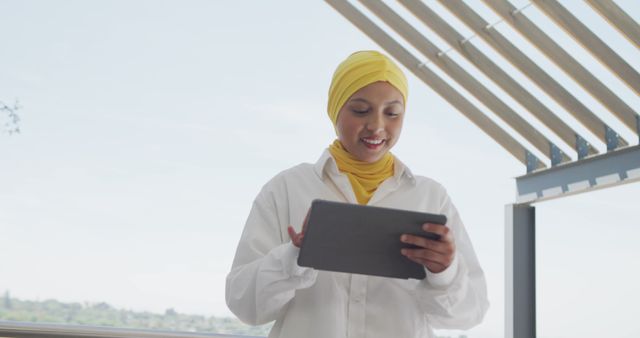 Muslim Woman in Yellow Hijab Using Tablet on Balcony - Download Free Stock Images Pikwizard.com