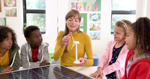 Teacher explaining renewable energy models to attentive students in classroom