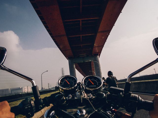 View from a motorcycle perspective, showing urban adventure and thrill of riding under an elevated highway. Ideal for promoting motorcycle gear, travel experiences, urban adventures, or infrastructure projects.