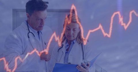 Doctors discussing patient data with ecg overlay in hospital corridor